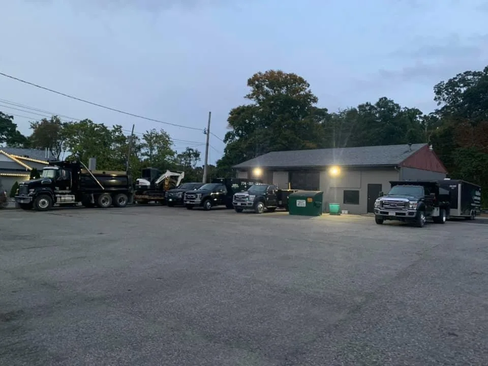 The daSilva Landscaping fleet of dump trucks and equipment parked at the yard at dusk