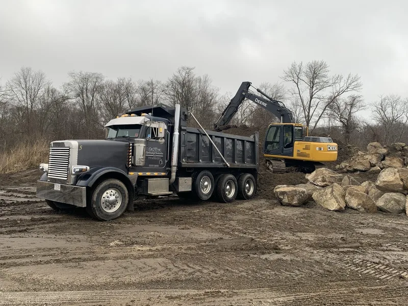Dump truck and excavator moving boulders at a job site