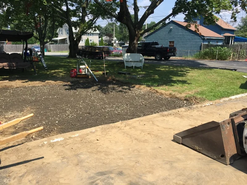 Lawn prep at a home with a skid steer bucket in view