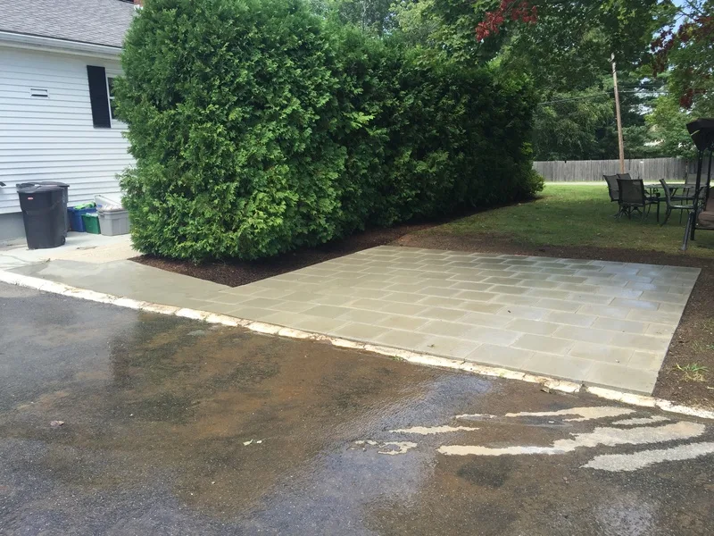 Paver patio beside a hedge and lawn