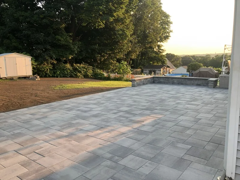 Large gray paver patio with a low wall at sunset