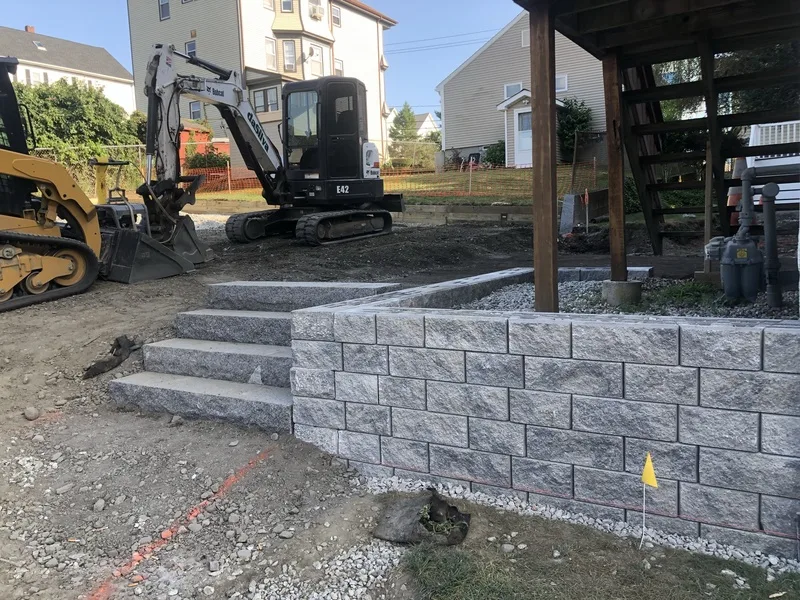 Block retaining wall with steps and an excavator