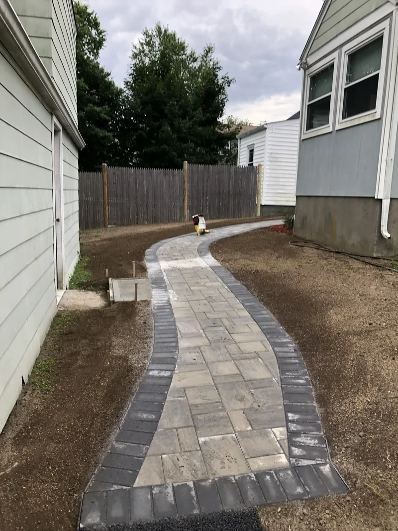 Paver walkway winding along the side of a house
